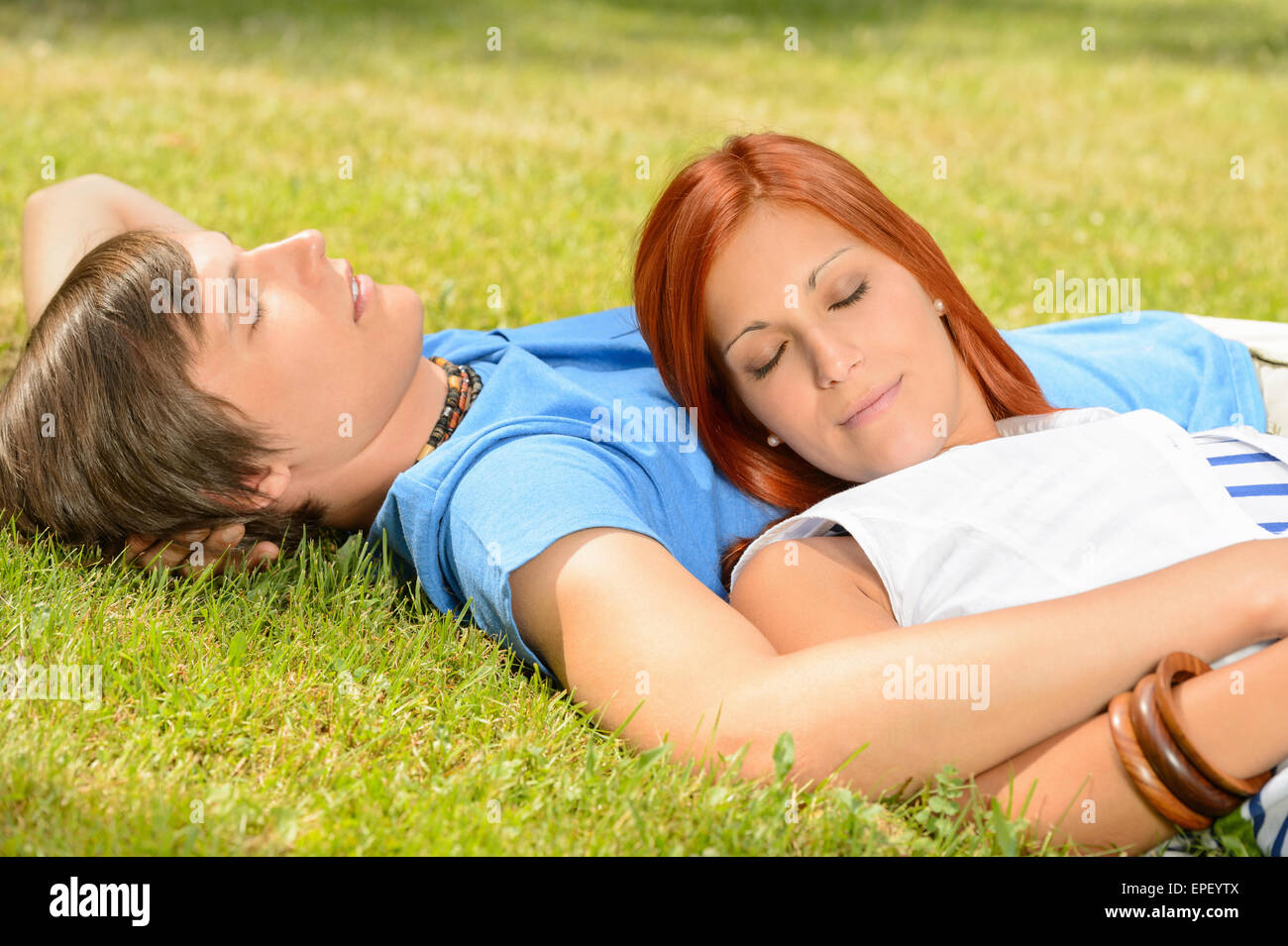 Teenage couple relaxing on grass closed eyes Stock Photo - Alamy