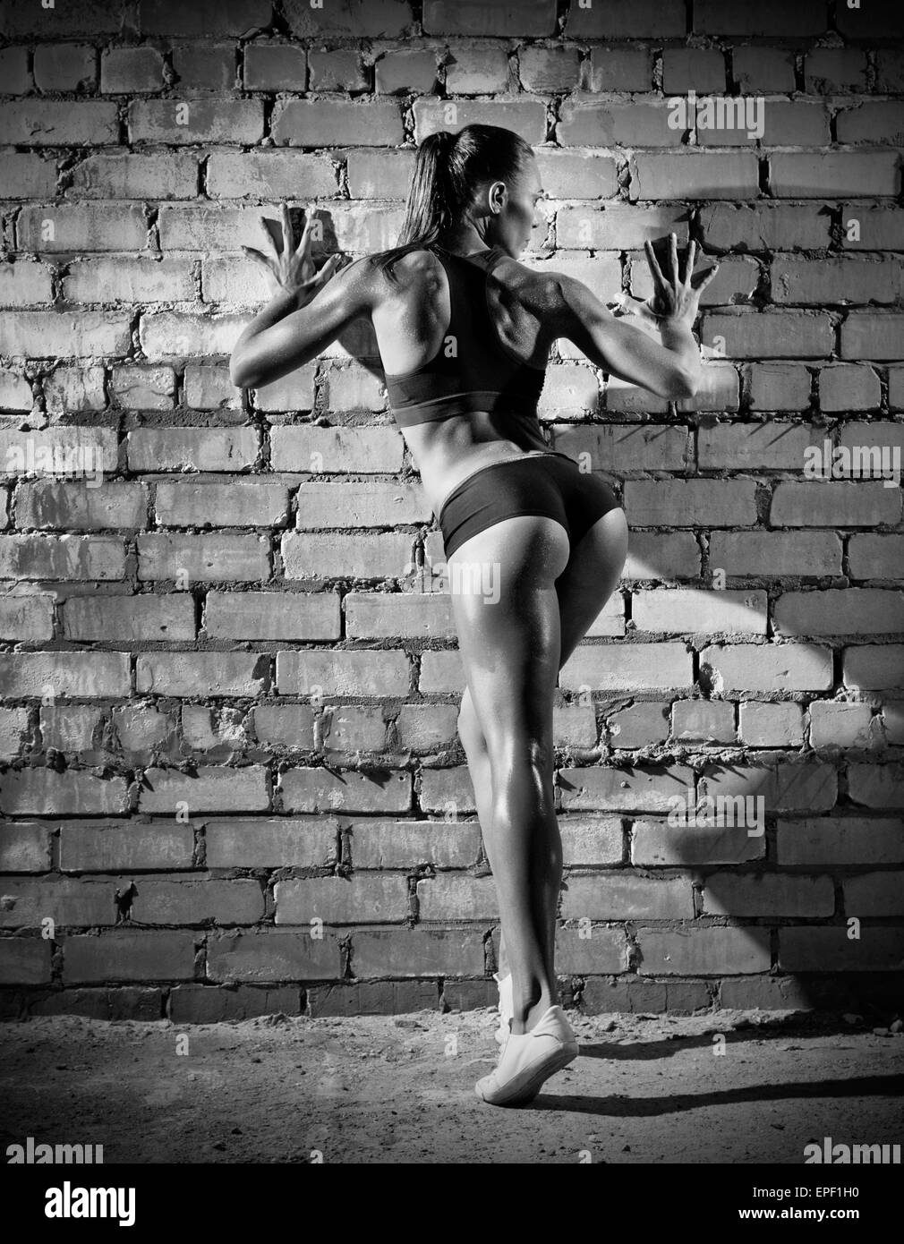 Muscular woman on grey brick wall (monochrome version) Stock Photo
