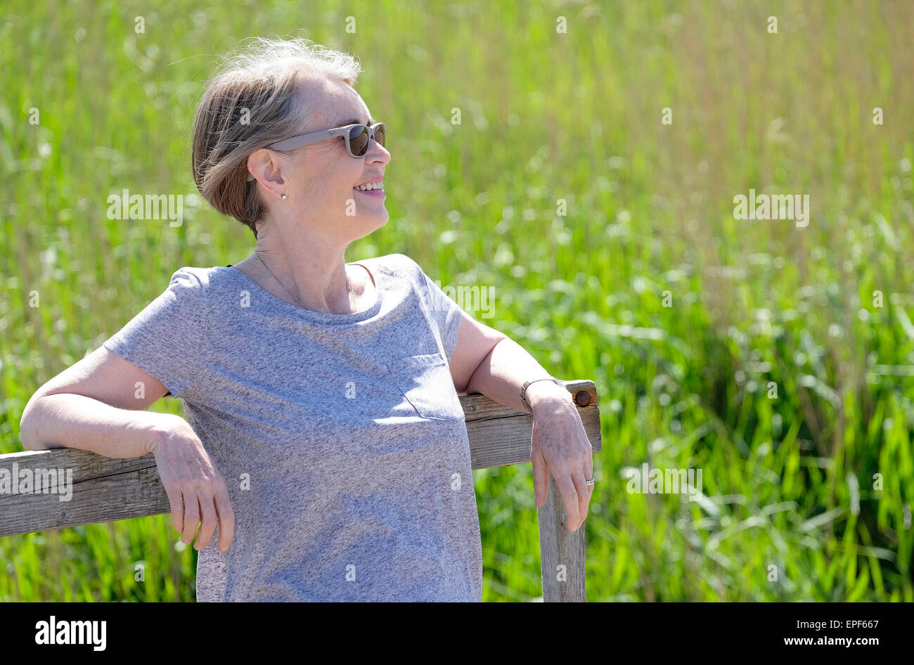 senior woman leaning on timber railing fence posts Stock Photo