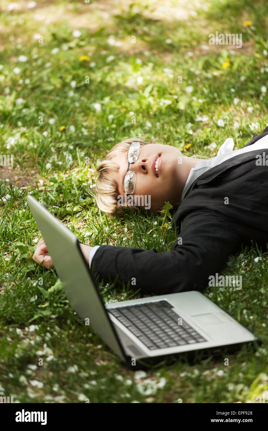 Happy business woman with laptop lying on grass Stock Photo - Alamy