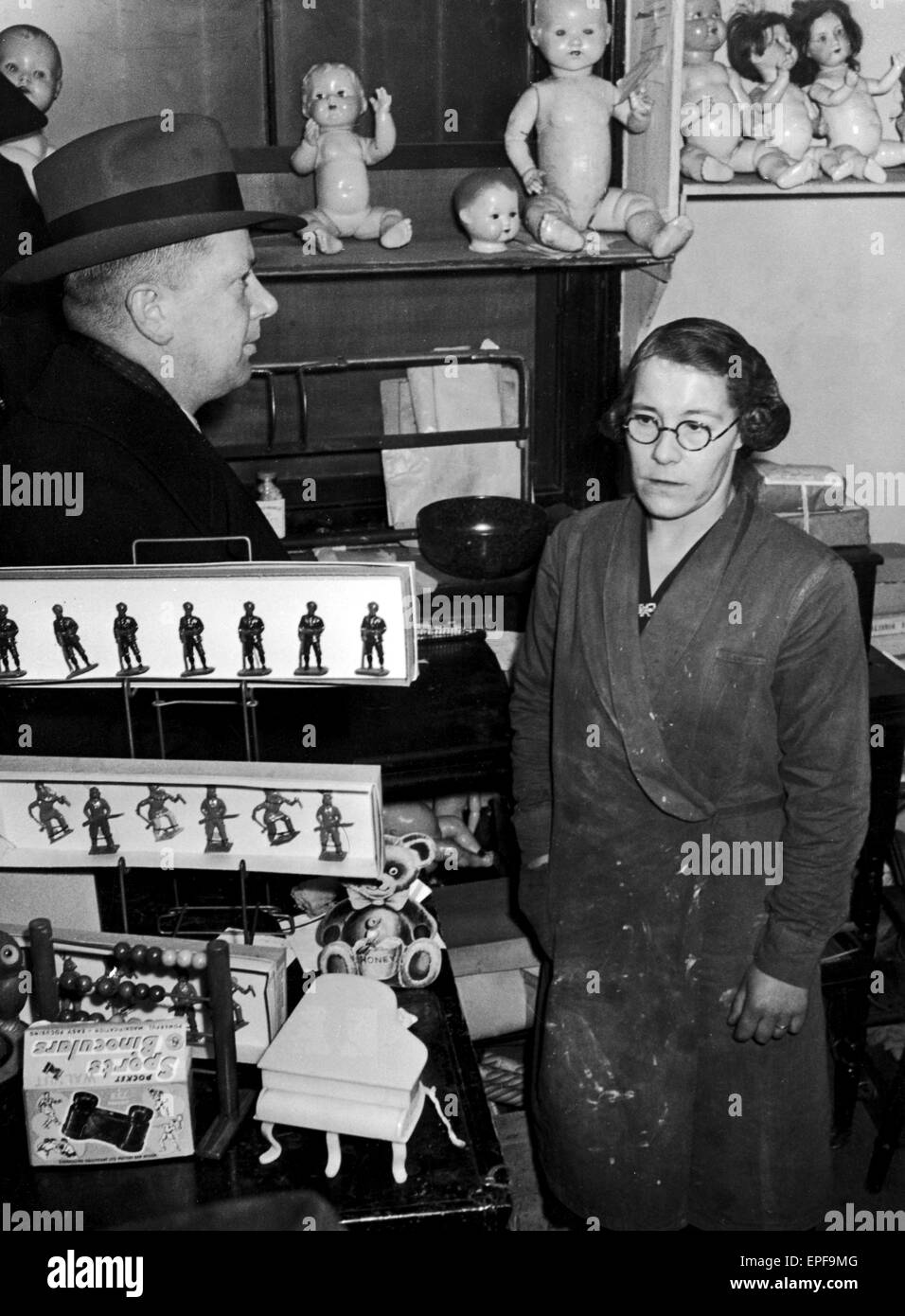 Detective - Sergeant T. Aspinall pictured interviewing Mrs. Daisy Rowntree amid dolls and lead soldiers in the Fulham toy shop and Doll's Hospital once owned by the missing Dr. and Mrs. Henderson. 7th March 1949. Stock Photo
