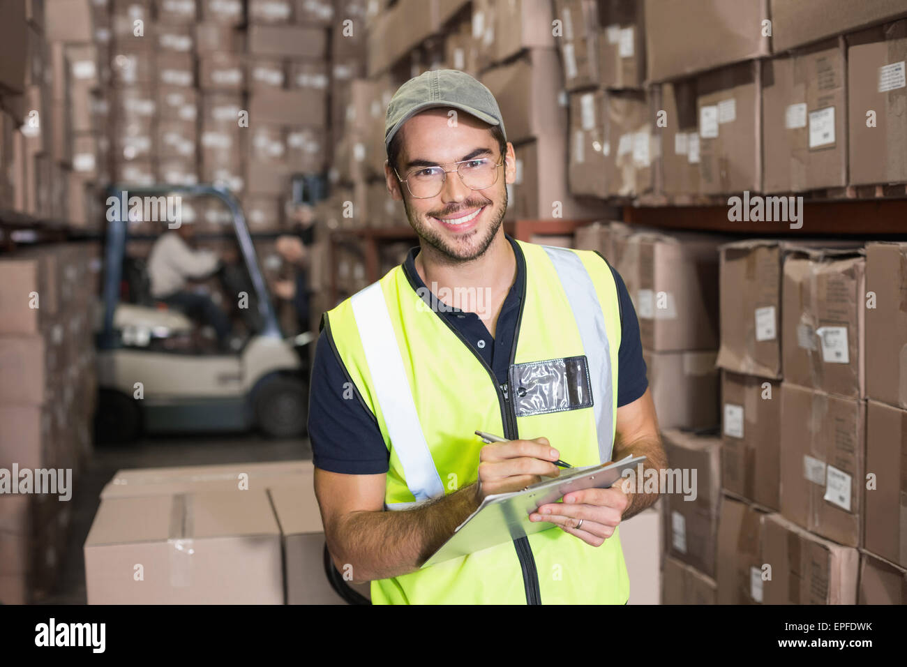 Warehouse worker smiling at camera with clipboard Stock Photo