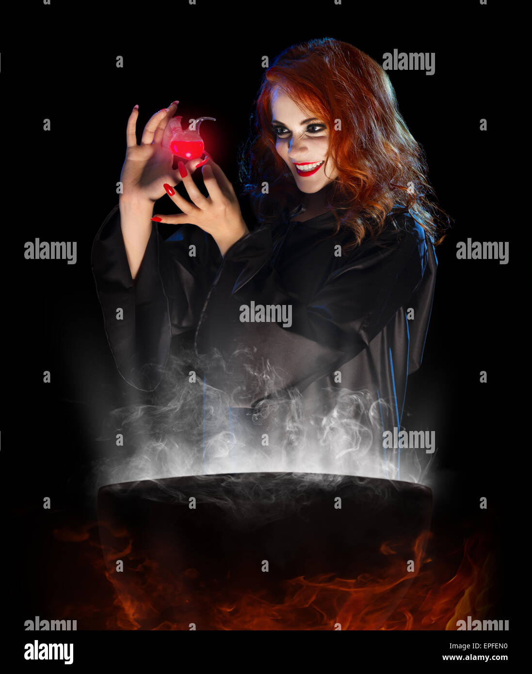 Young witch with red potion and cauldron isolated Stock Photo