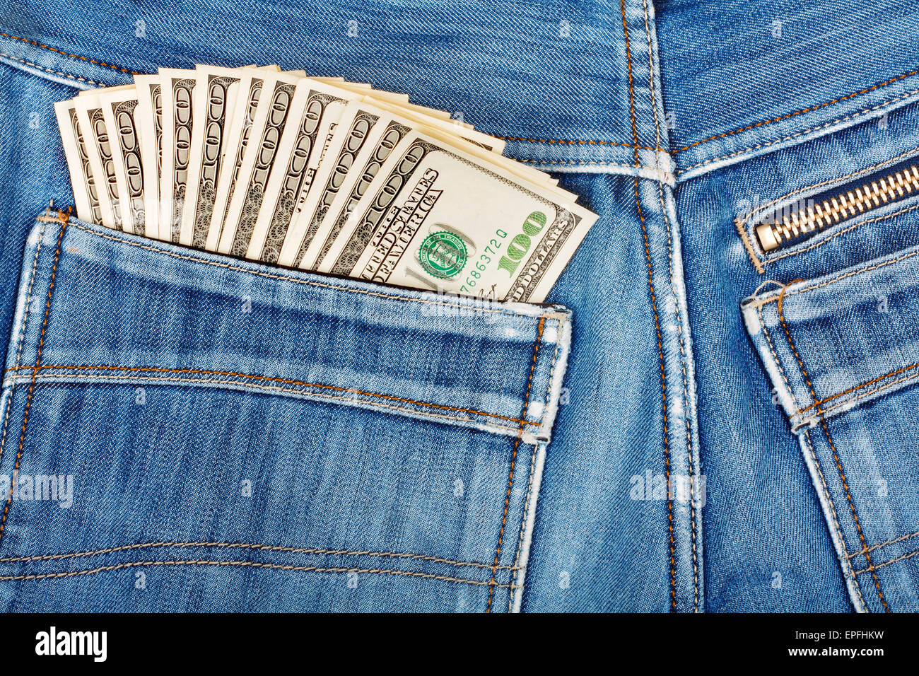 A hundred dollar bills sticking in the back pocket of denim blue jeans Stock Photo