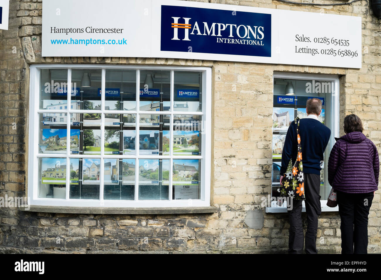 A couple looking at house prices in the window of Hamptons
