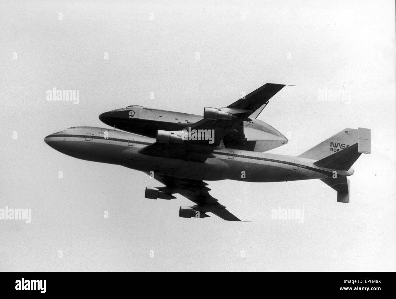 Space Shuttle Enterprise, piggy back on a NASA 747 Jumbo Jet, flies over Manchester Airport at 11 o'clock, sweeping in from Heard Green Area at 600ft. After a slow glide down the route of the runway, the shuttle slowly climbed up to 1000ft and was gone in Stock Photo