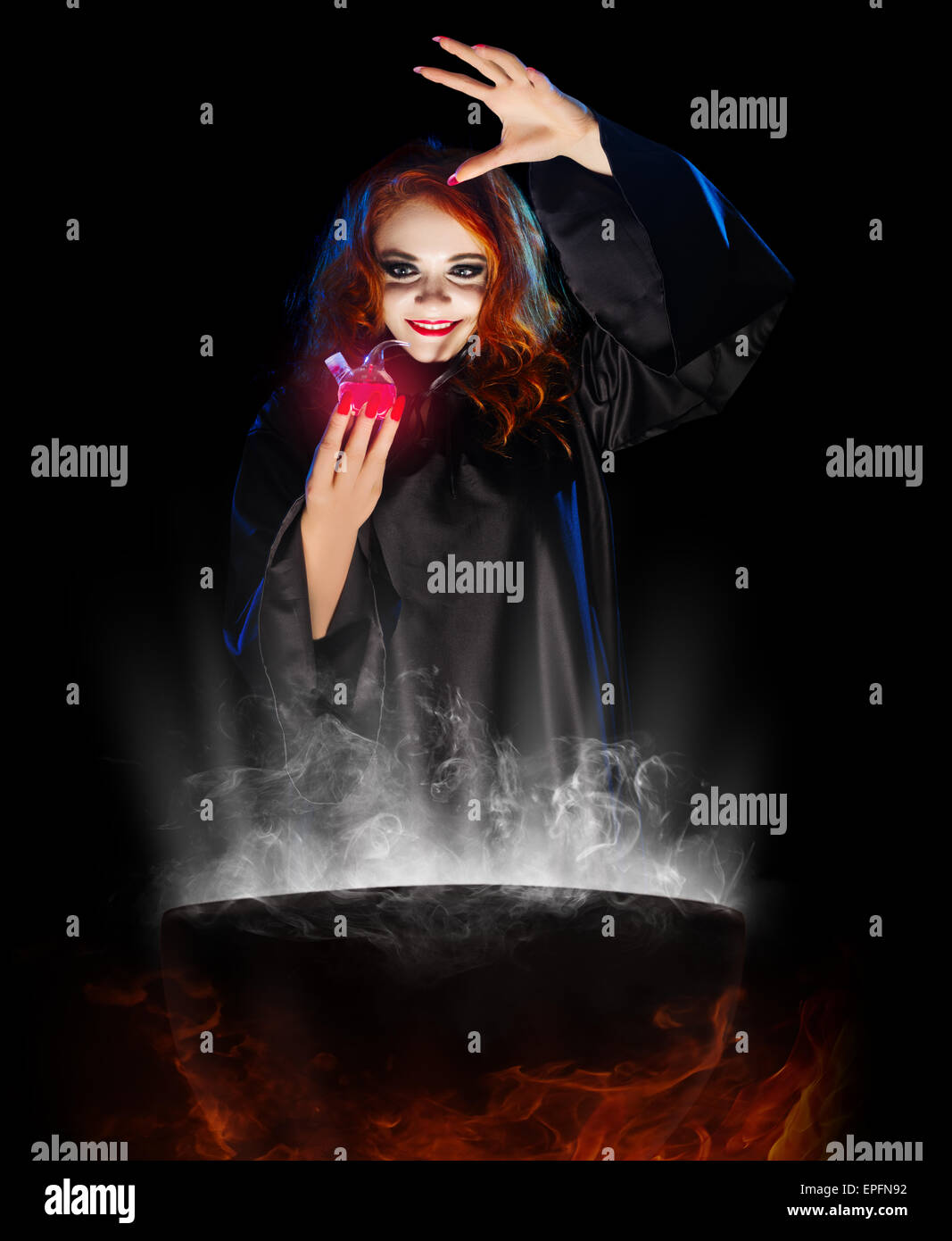 Young witch with red potion and cauldron  isolated Stock Photo