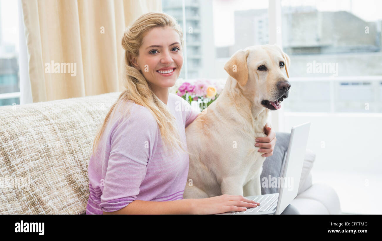 Beautiful blonde relaxing on the couch with pet dog Stock Photo - Alamy