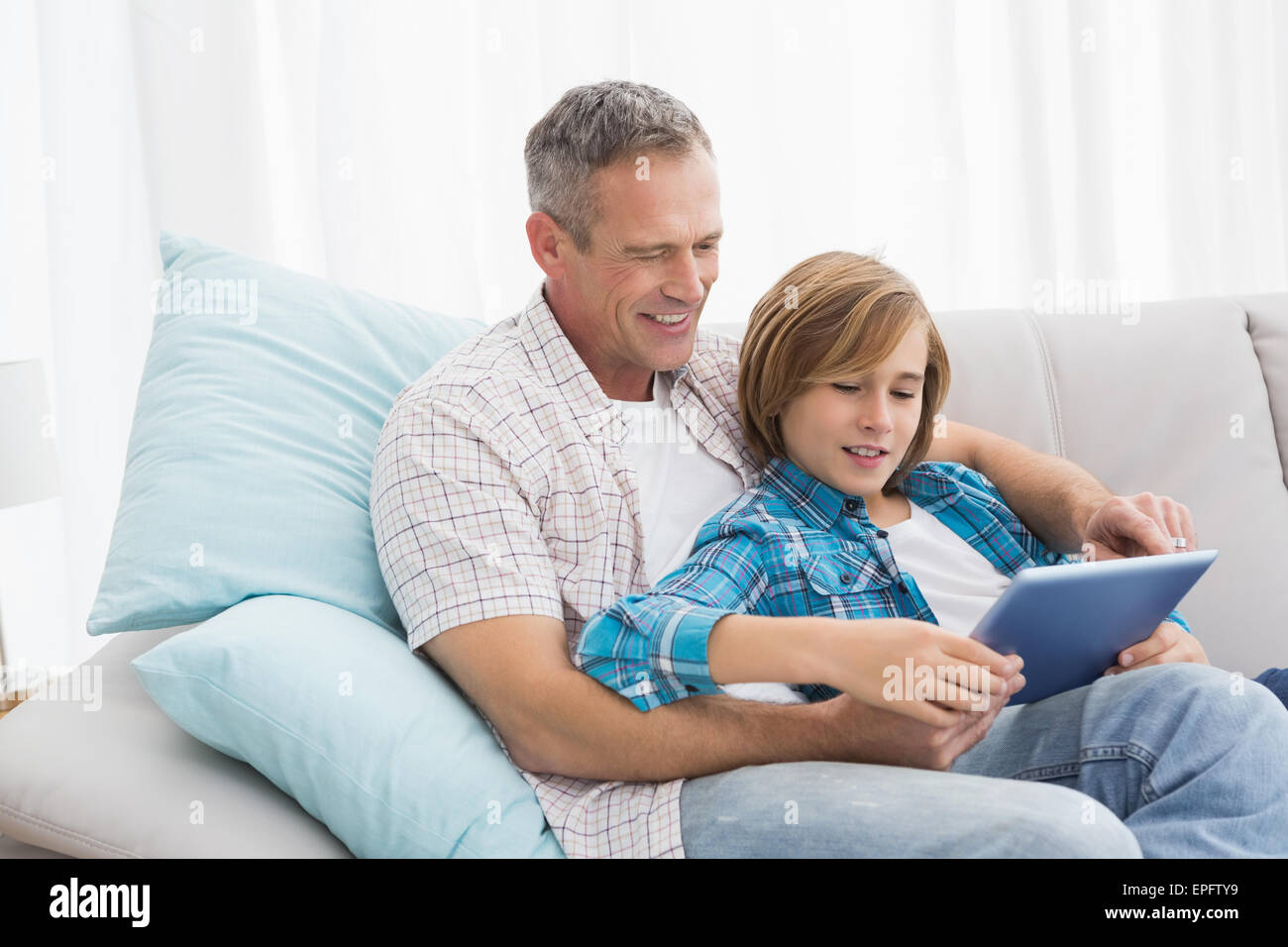 Father with son relaxing on the couch using laptop Stock Photo