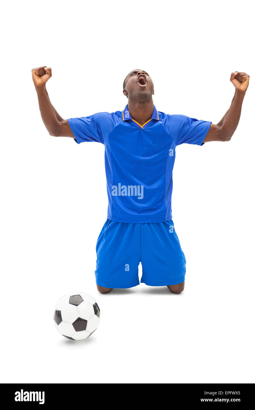 Excited football player in blue cheering on his knees Stock Photo