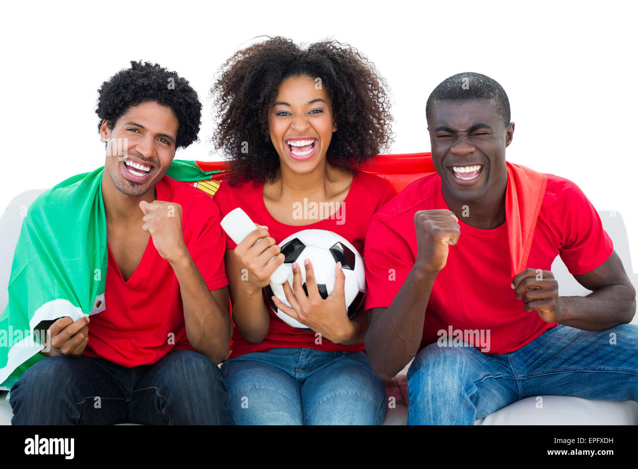 Cheering football fans in red sitting on couch with portugal flag Stock Photo