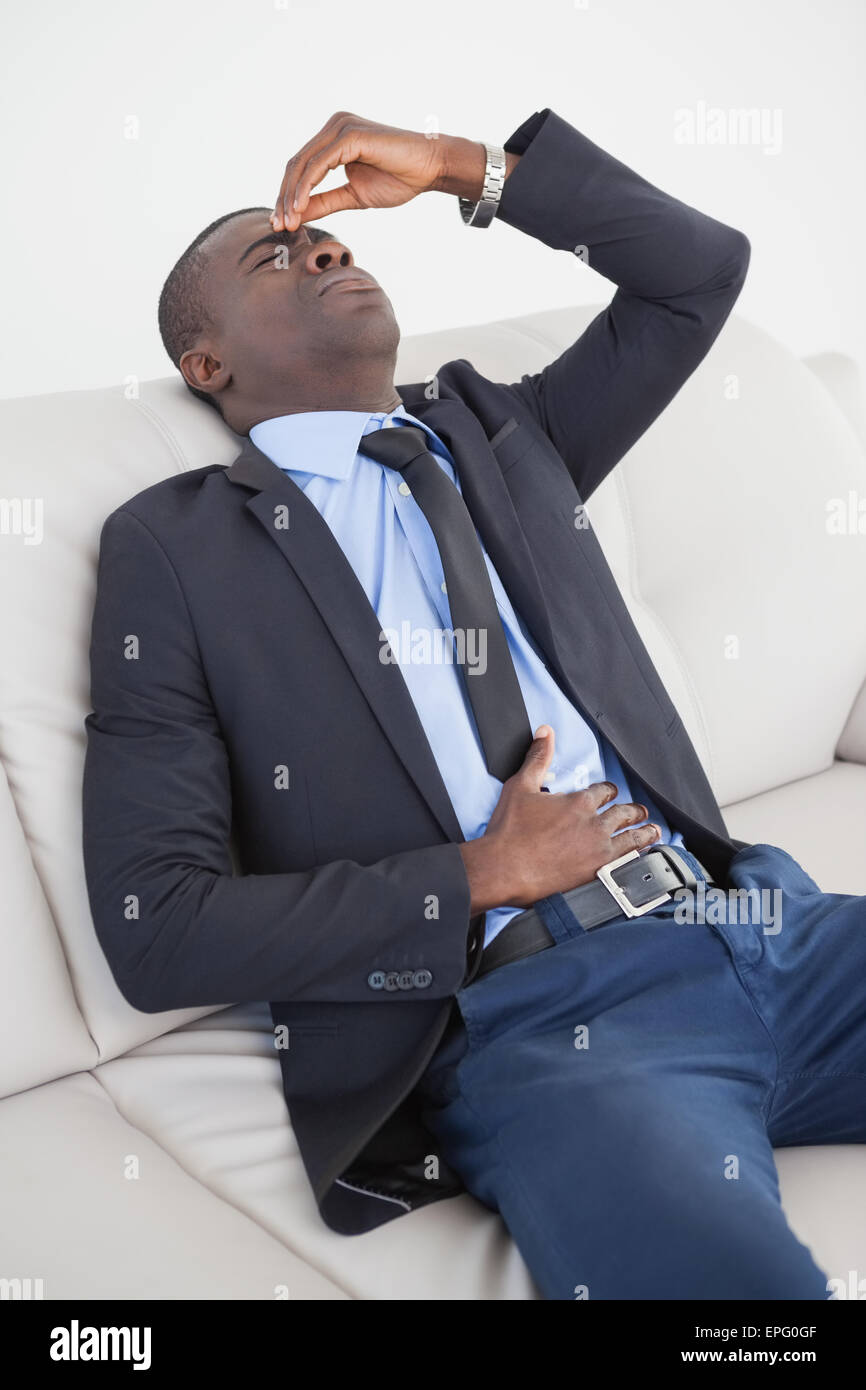 Tired businessman getting headache on the sofa Stock Photo