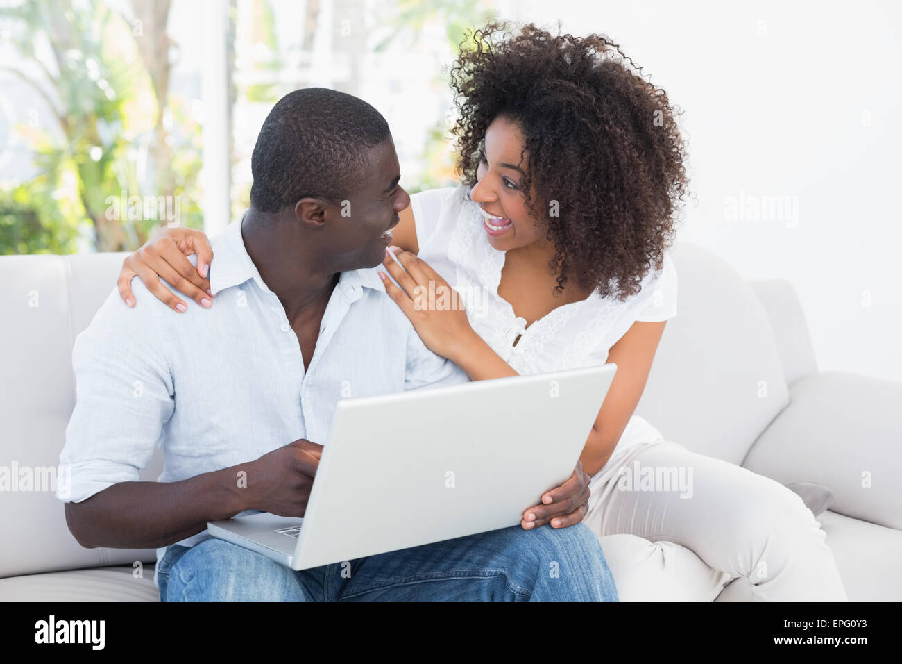 Attractive couple using laptop together on sofa Stock Photo - Alamy