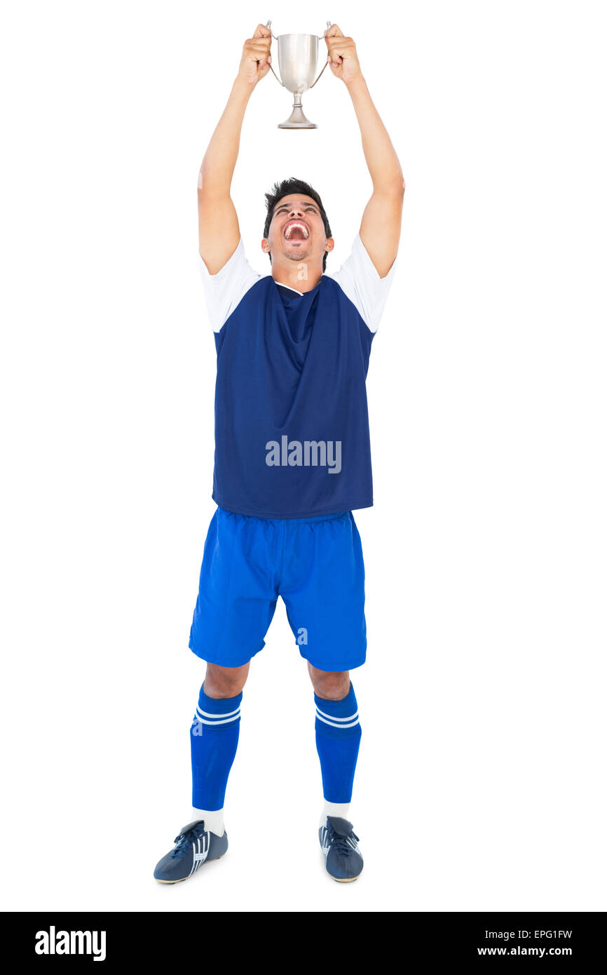 Football player in blue holding winners cup Stock Photo