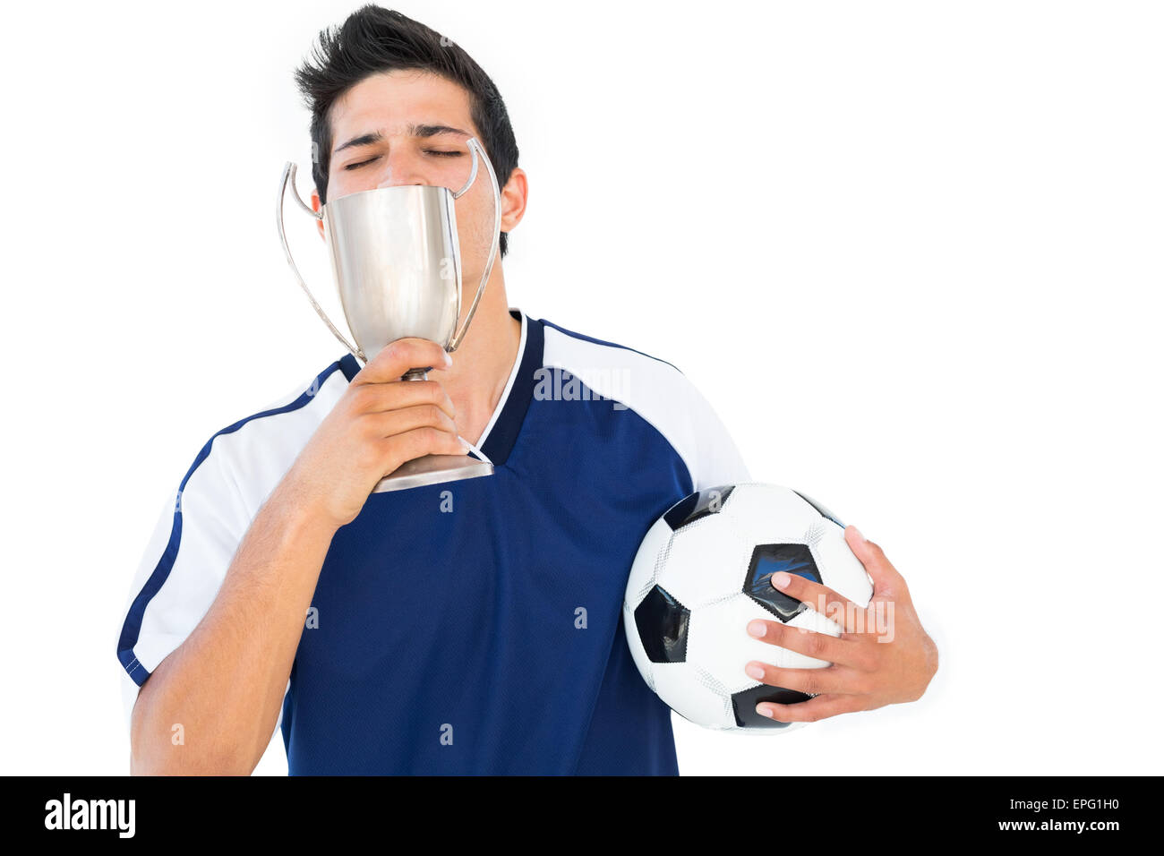 Football player in blue holding winners cup and ball Stock Photo