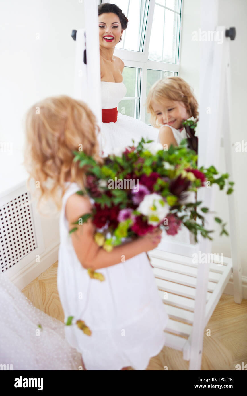 Smiling happy bride and a flower girl indoors Stock Photo - Alamy