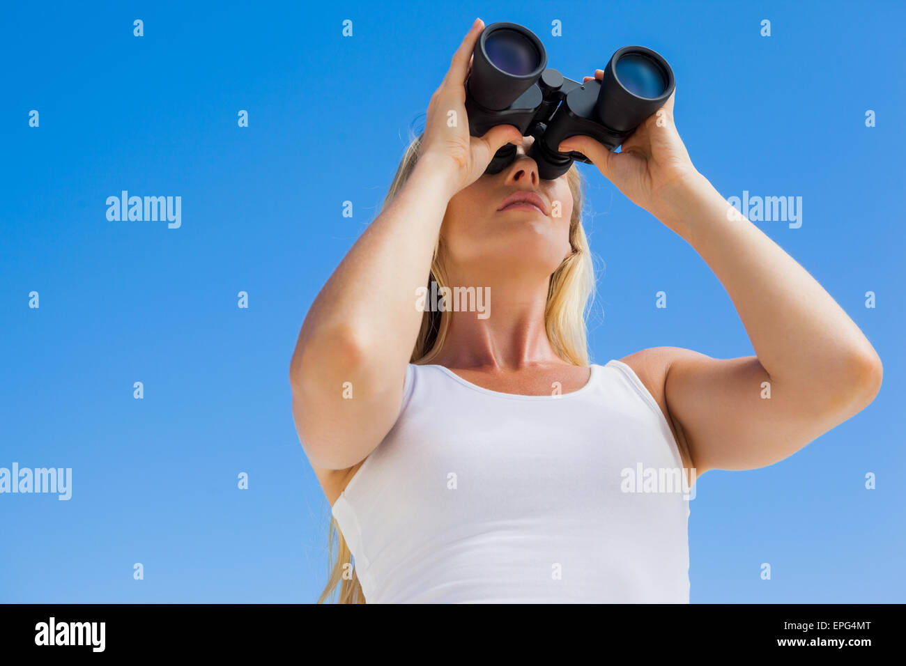 Blonde looking through binoculars on the beach Stock Photo Alamy