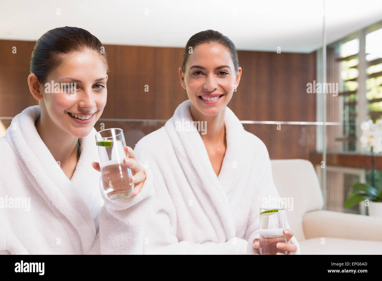 Smiling women in bathrobes drinking water Stock Photo Alamy