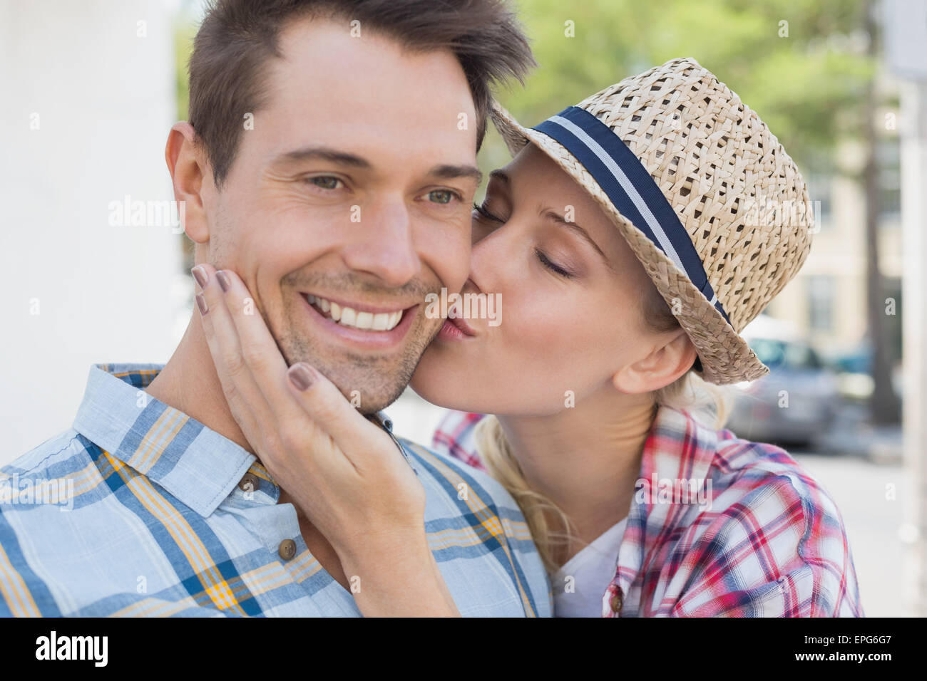 Young hip couple smiling at camera woman kissing mans cheek Stock Photo ...