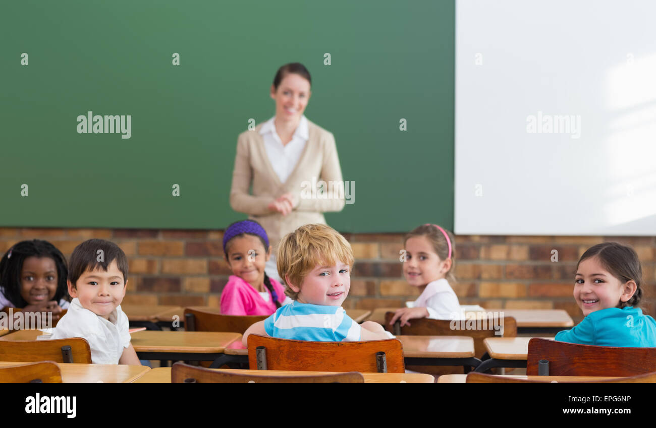 Cute pupils and teacher smiling at camera in classroom Stock Photo - Alamy