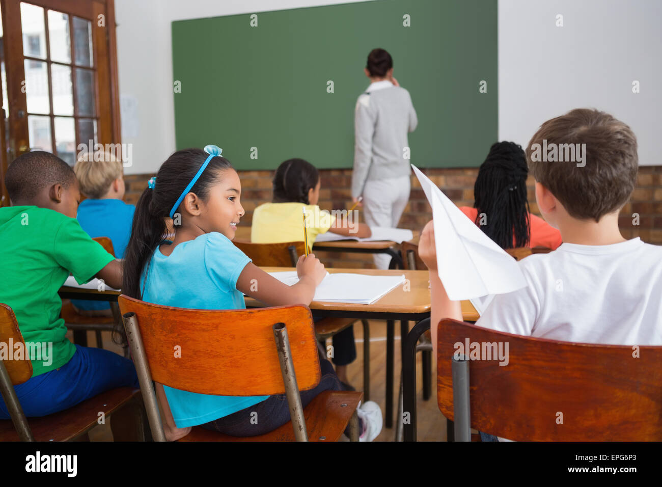 Naughty pupil about to throw paper airplane in class Stock Photo