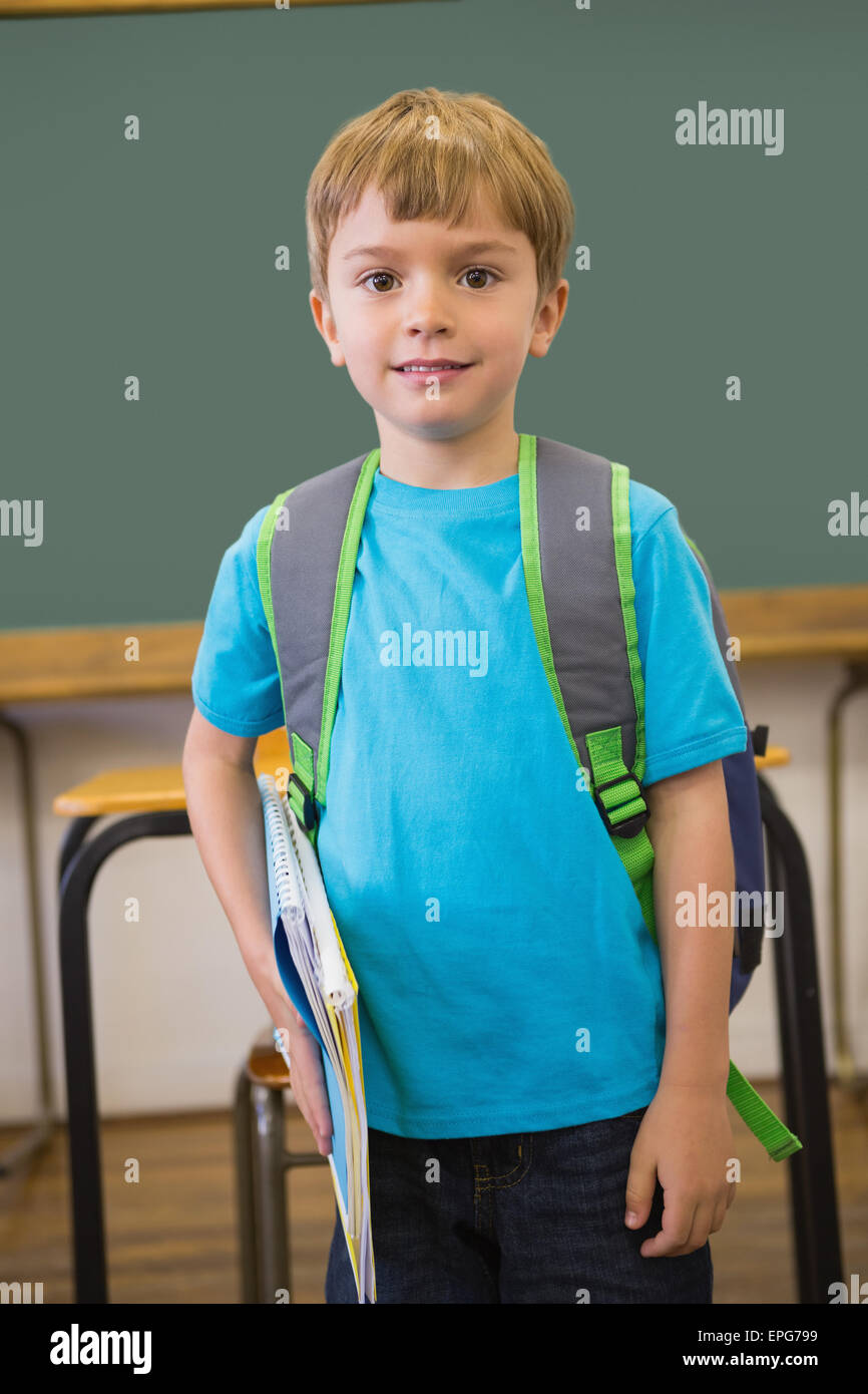 Cute pupil smiling at camera in classroom holding notepad Stock Photo ...