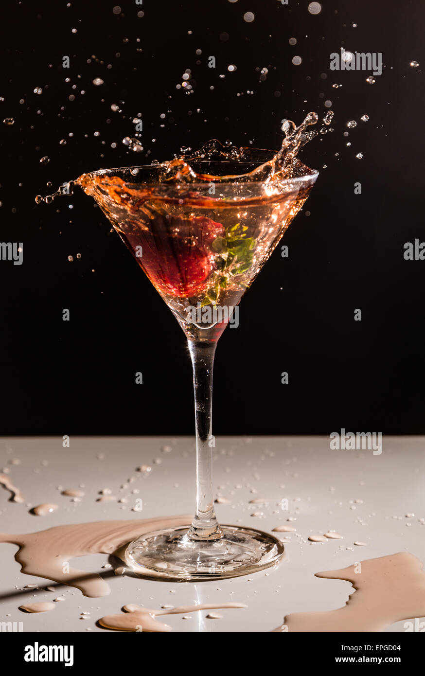 A strawberry dropping into a cocktail glass Stock Photo