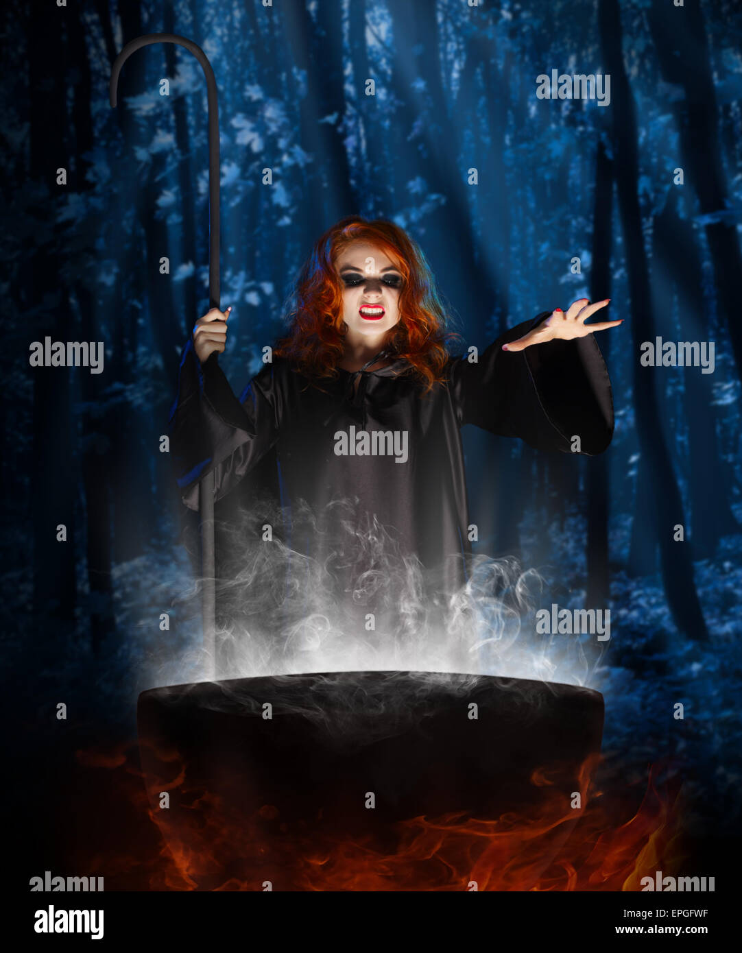 Young witch with cauldron at night forest Stock Photo