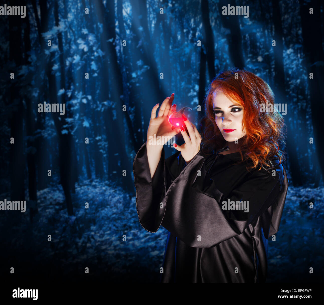 Young witch with potion at night forest Stock Photo