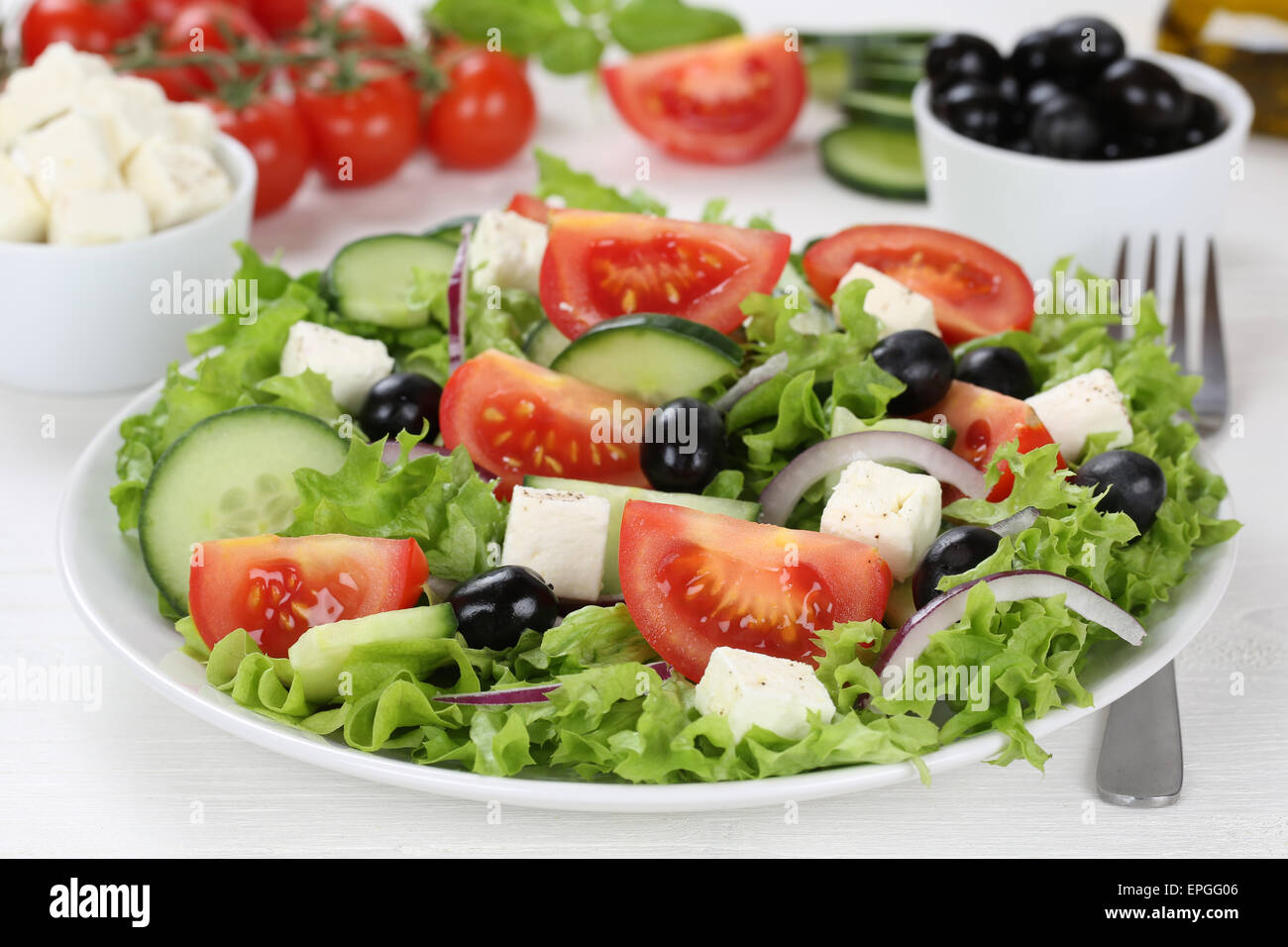 Griechischer Salat auf Teller, Tisch mit Tomaten, Feta K├ñse und Oliven Stock Photo