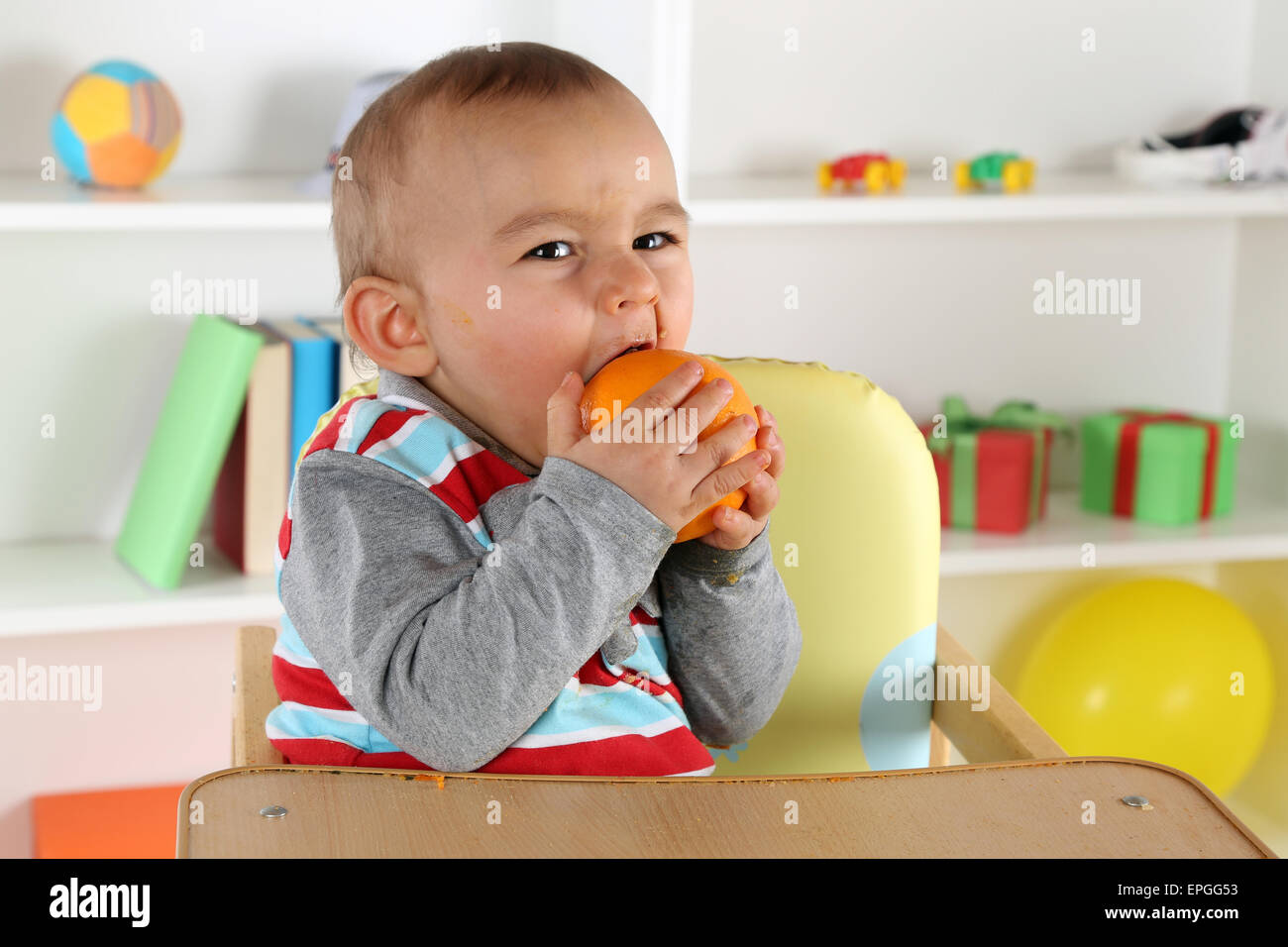 Baby Kind beim Essen einer Orange Frucht Stock Photo