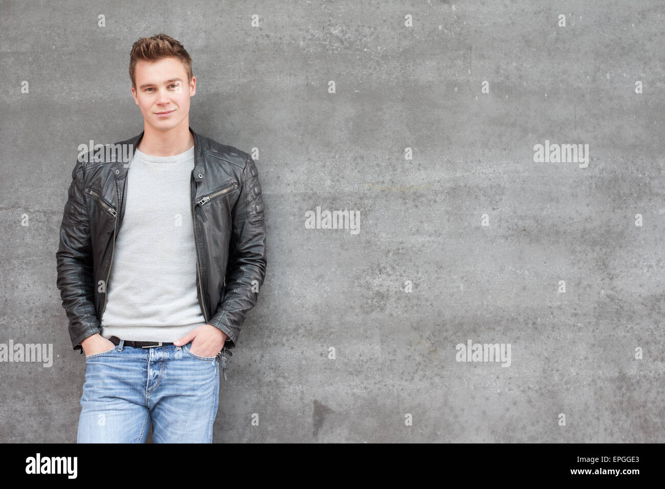 Casual young guy in front of concrete wall Stock Photo