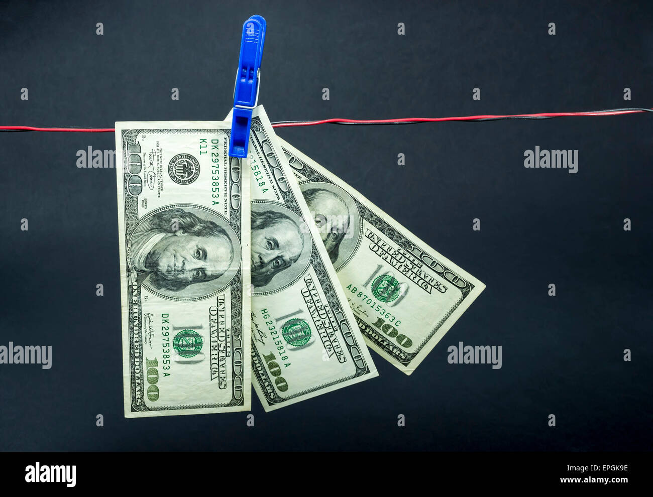 Three hundred dollar bills held with a clothes pin on black background, concept for money laundry or financial fraud Stock Photo