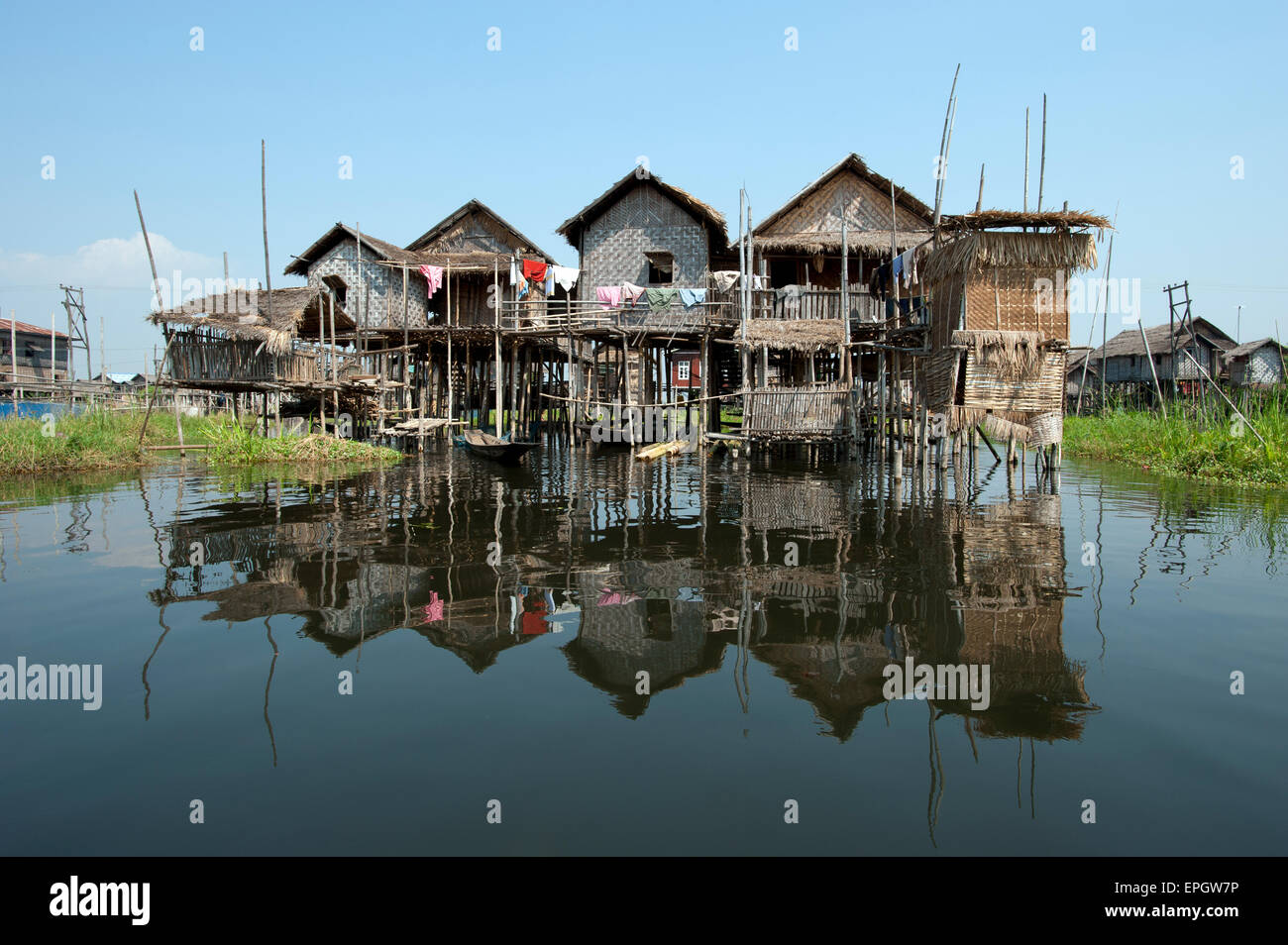 Stilted Community Wooden stilted homes of a village cast a reflection in the calm waters ...