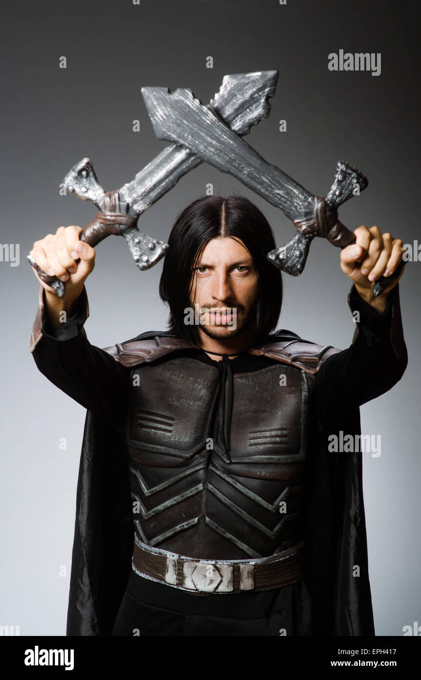 Angry knight with sword against dark background Stock Photo - Alamy