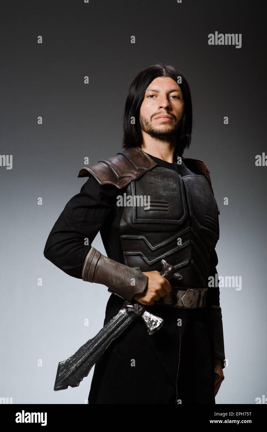 Angry knight with sword against dark background Stock Photo - Alamy