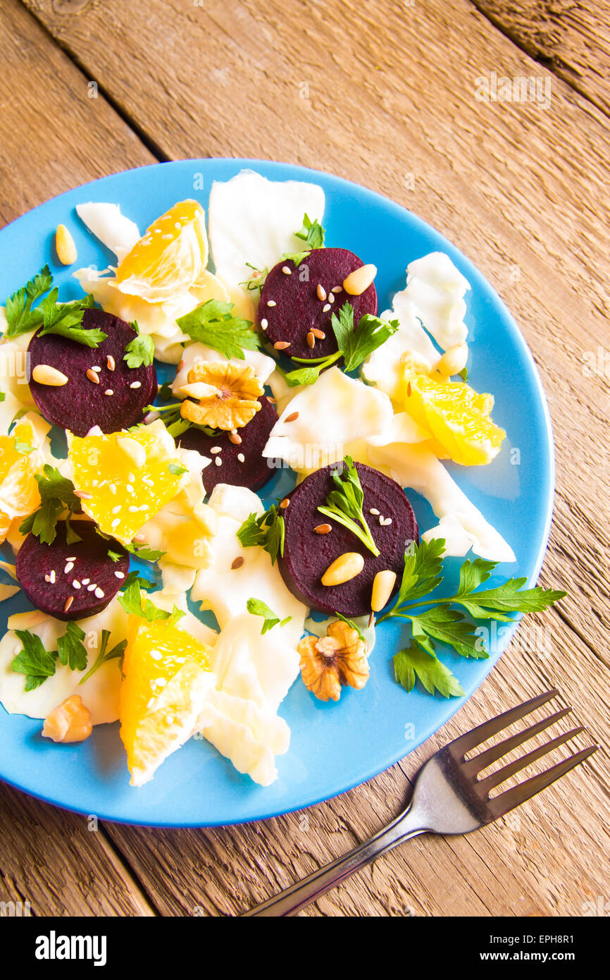 Vegetable and fruit salad with beet and nuts over rustic wooden table