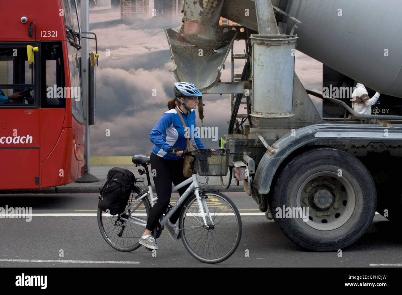 Woman cyclist starts to overtake a stationary cement mixer lorry in Shoreditch, London. Stock Photo