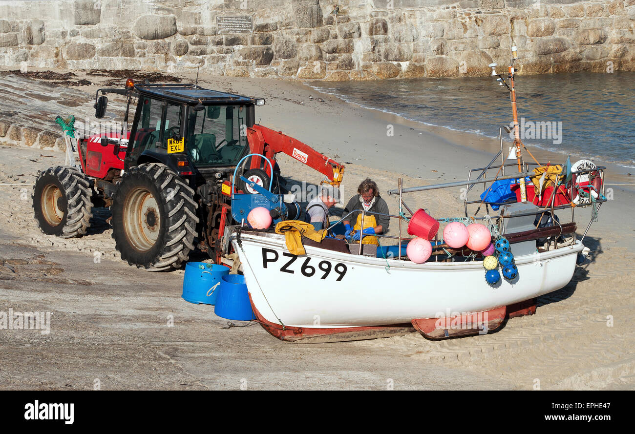 Two fishermen with their boat on the harbour slipway at Sennen Cove in Cornwall, UK Stock Photo