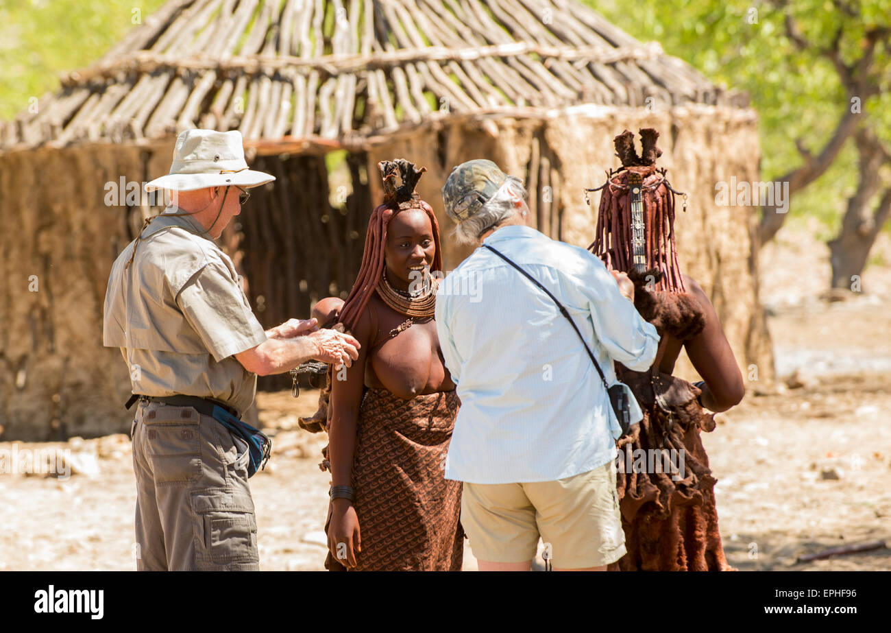 Africa, Namibia. Himba Tribe Village. Tourists help native women