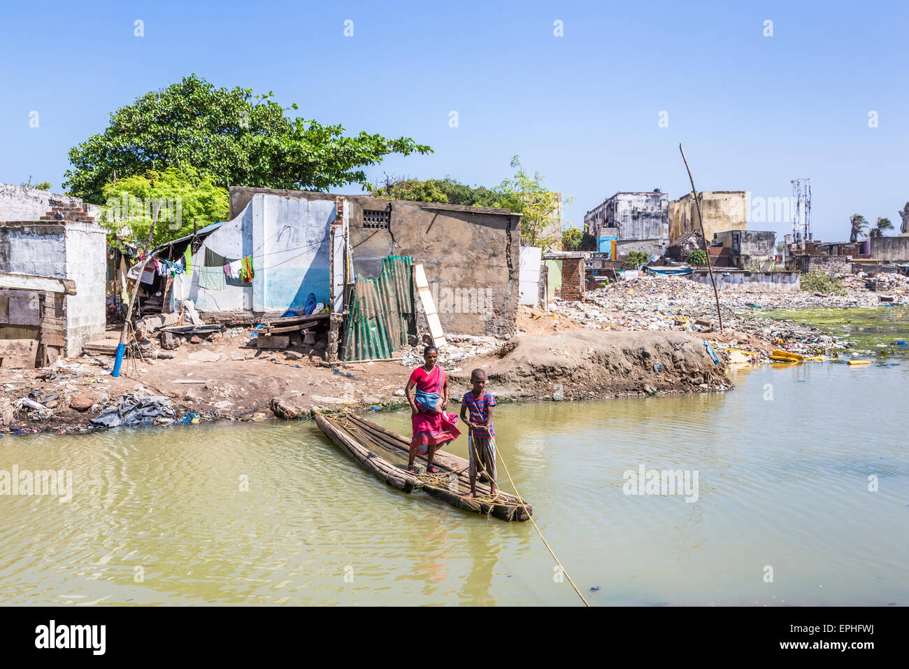 Boy operating a makeshift wooden ferry across the Adyar River in slums on the ocean shore, Chennai, Tamil Nadu, southern India Stock Photo