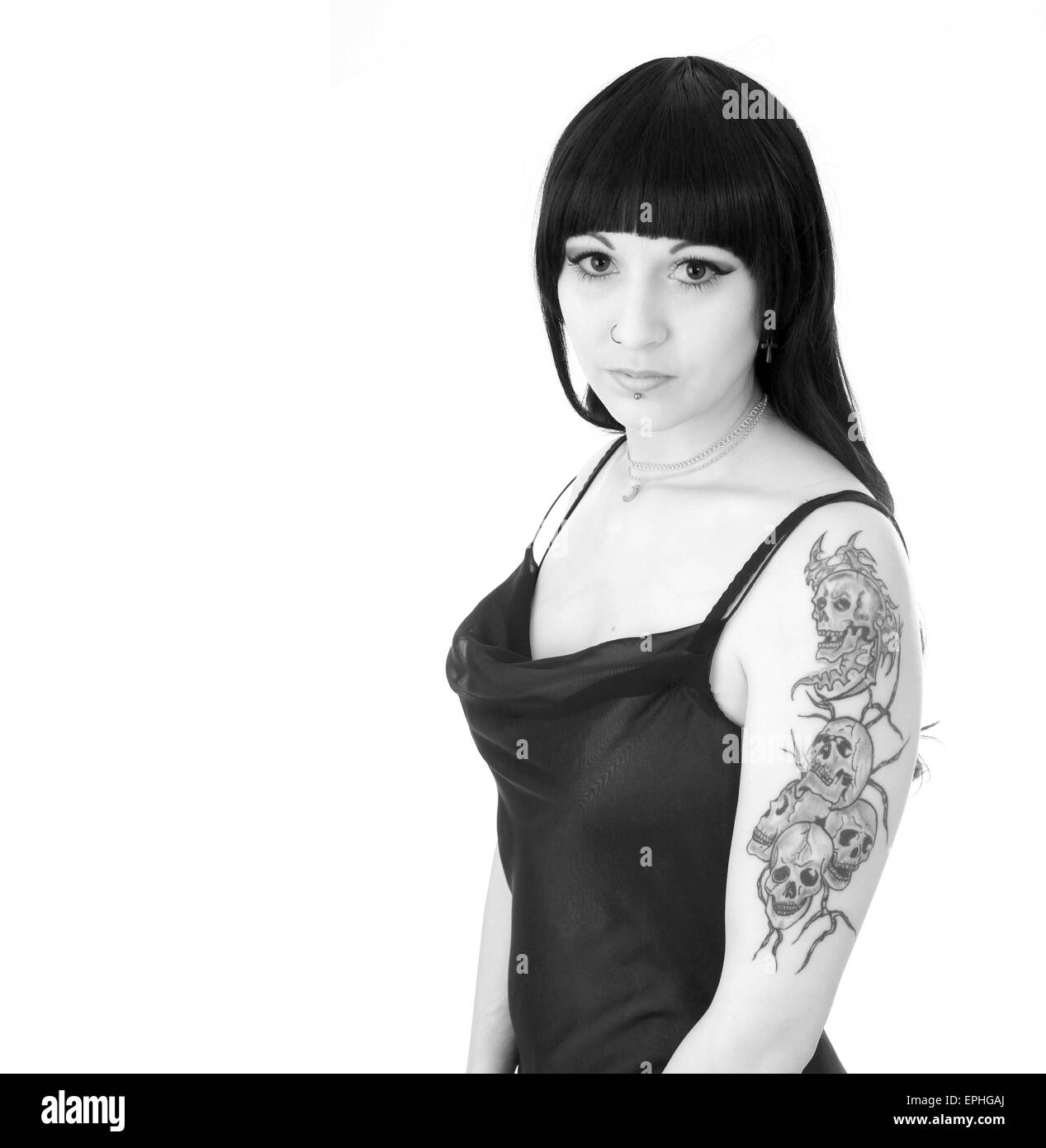 Beautiful young woman showing her skull tattoo's on her upper arm while in an evening dress Stock Photo