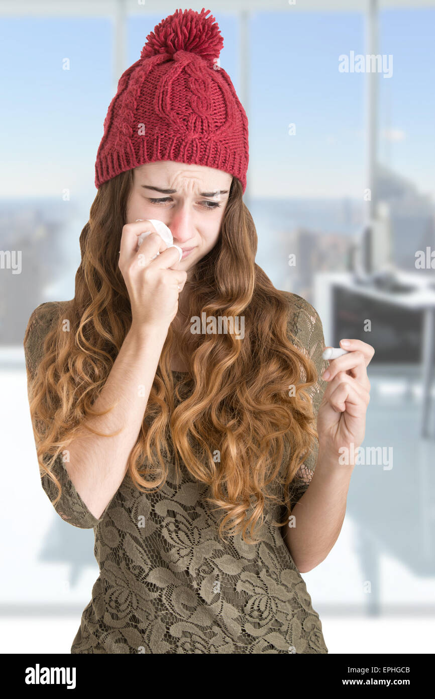 Pale sick woman with a flu checking if she has a fever with a thermometer in an office Stock Photo