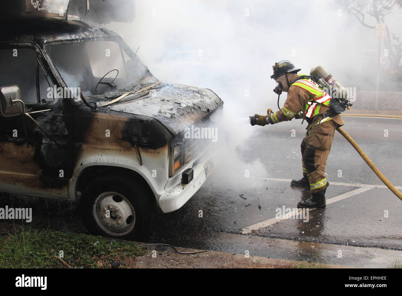 Unknown fireman spraying water on a vehicle fire Stock Photo