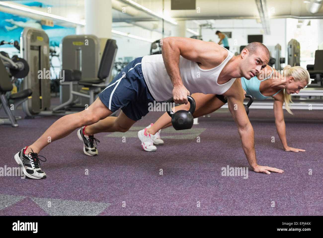 Fit couple doing push ups with kettle bells in gym Stock Photo - Alamy