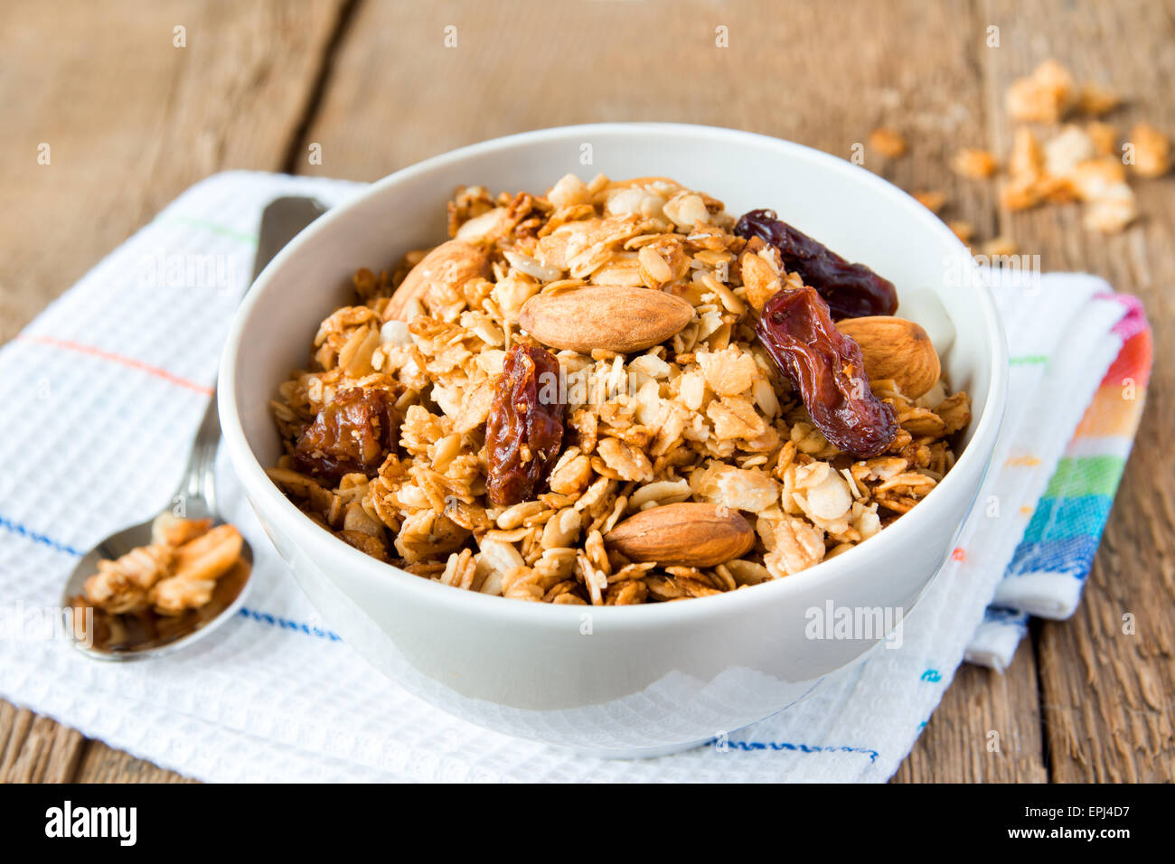 wholegrain muesli for breakfast, with lots of dry fruits, nuts and grains close up, horizontal, on wooden table with spoon Stock Photo