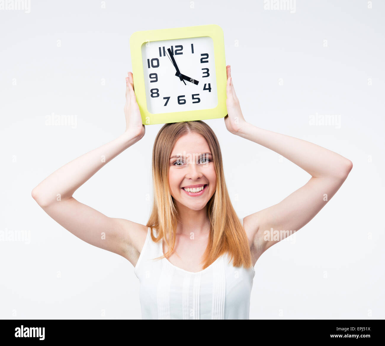Happy woman holding big clock on head isolated on a gray background ...