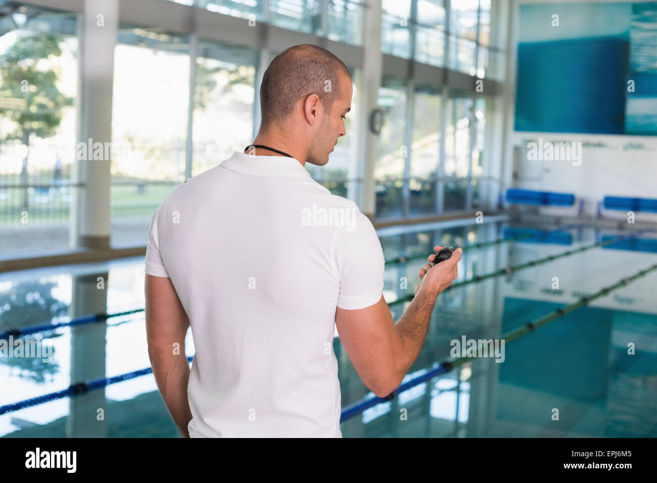 Swimming coach looking at stopwatch by pool at leisure center Stock ...
