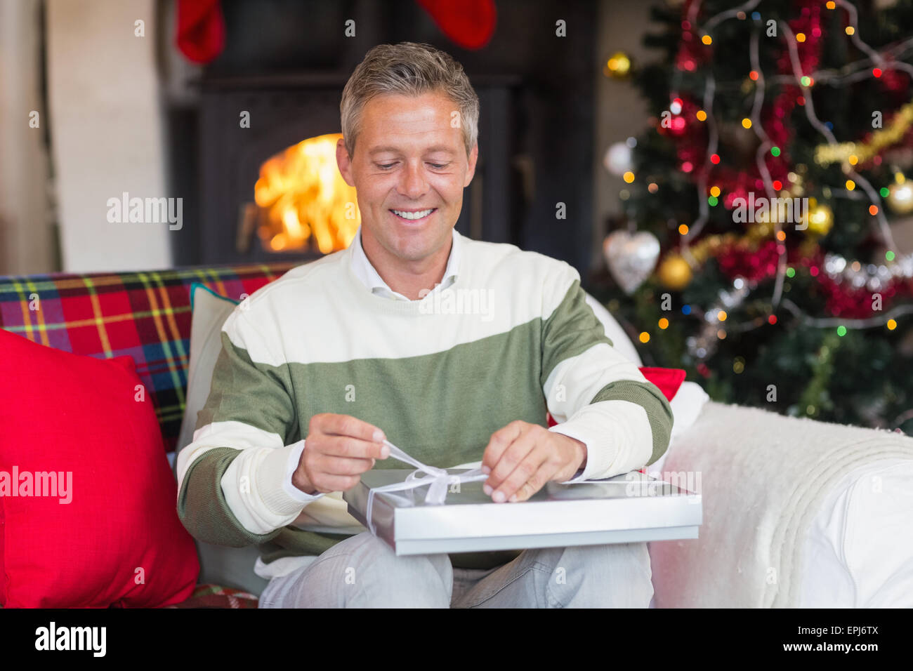Man opening a gift on the couch at christmas Stock Photo