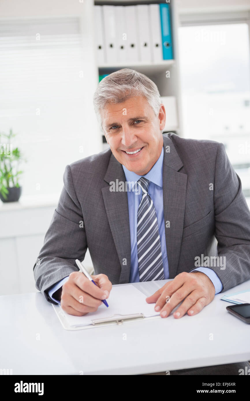 Smiling businessman writing on clipboard Stock Photo - Alamy